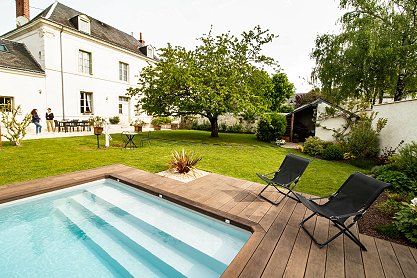 Une terrasse en bois avec un salon de jardin et une piscine dans le fond